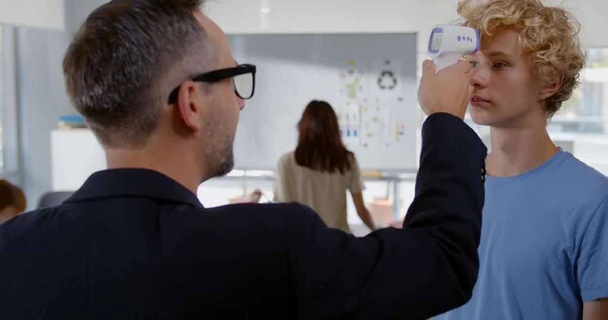 Nauczyciel mężczyzna mierzy temperaturę ucznia termometrem