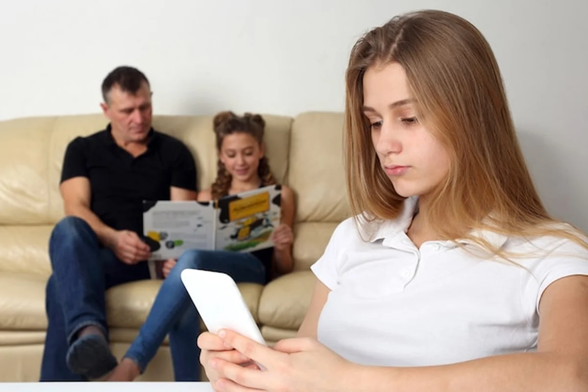 Nastoletnia dziewczyna patrzy w telefonie na rodzinę