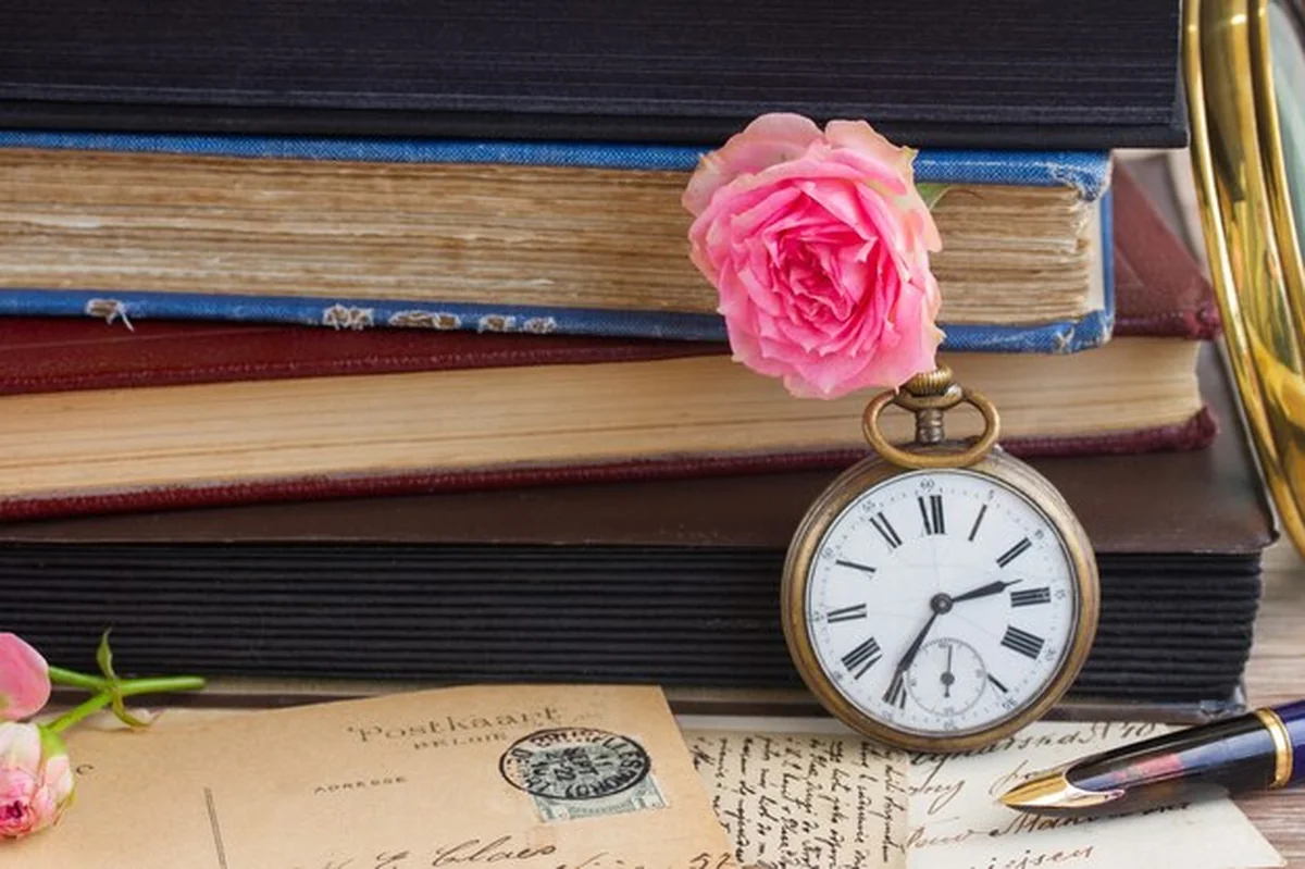 Antyczny zegar ze starymi książkami i literami w tle