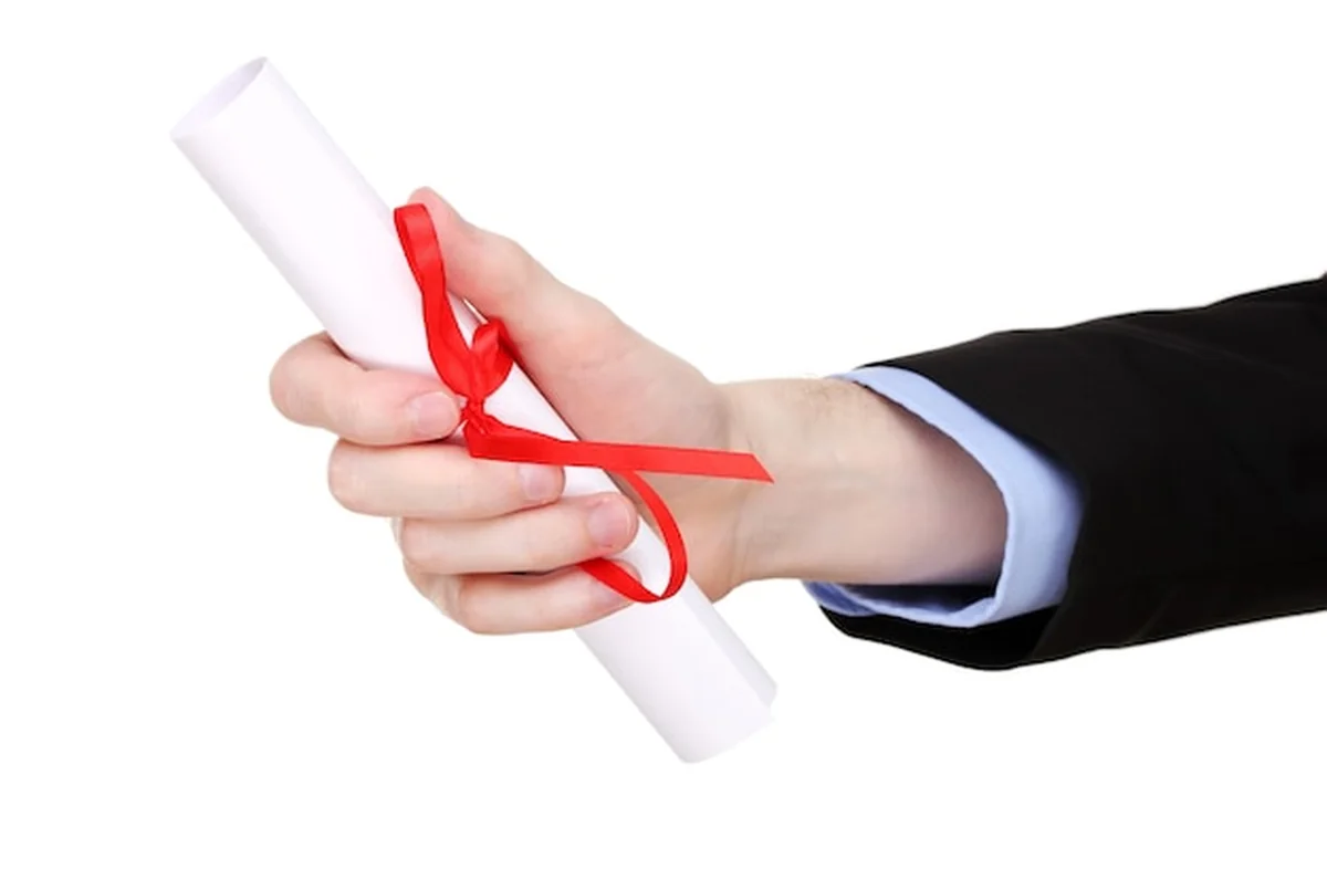 Dyplom ukończenia studiów w ręku na białym tle