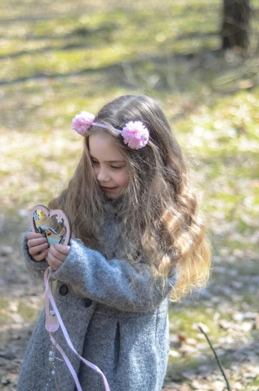 Dziewczyna w vintage ubraniu bawiąca się drewnianym sercem w lesie