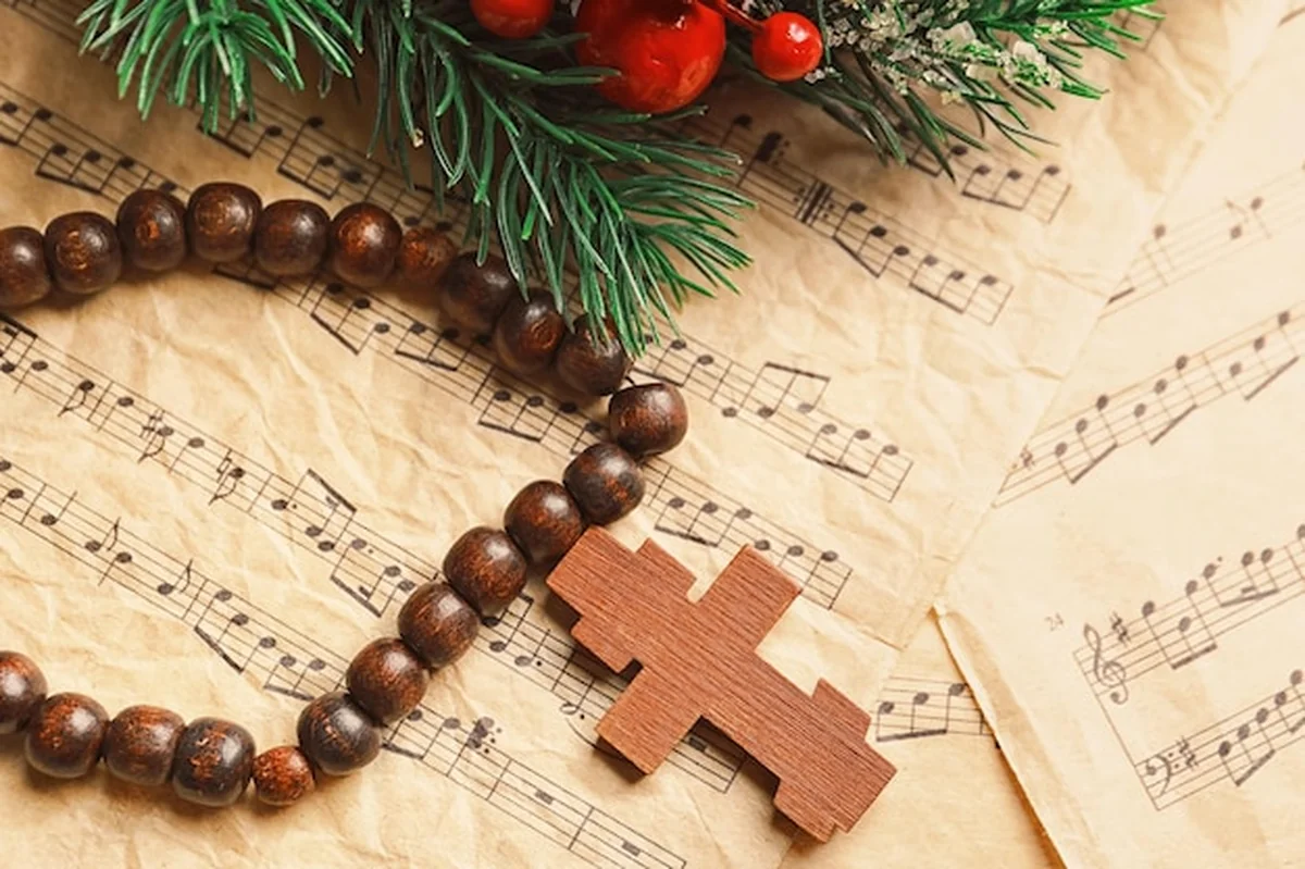 Świąteczna kompozycja z drewnianym krzyżem i nutami na stole