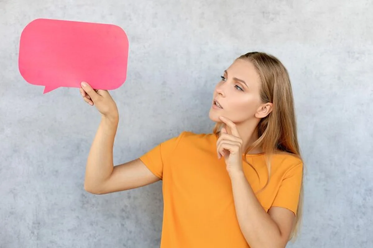 Młoda blond kobieta trzymająca pusty dymek na białym tle