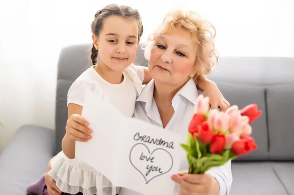 Mała dziewczynka daje babci bukiet różowych tulipanów