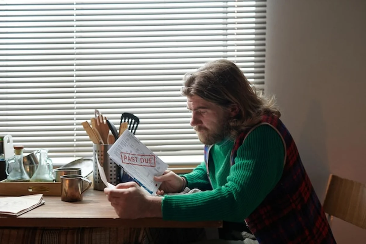 Osoba siedząca przy biurku z rachunkami i notatkami