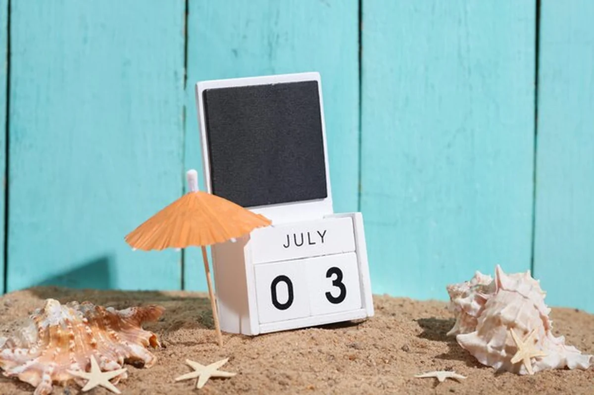 Kompozycja wakacyjna na plaży z pamiątkami morskimi i drewnianym kalendarzem