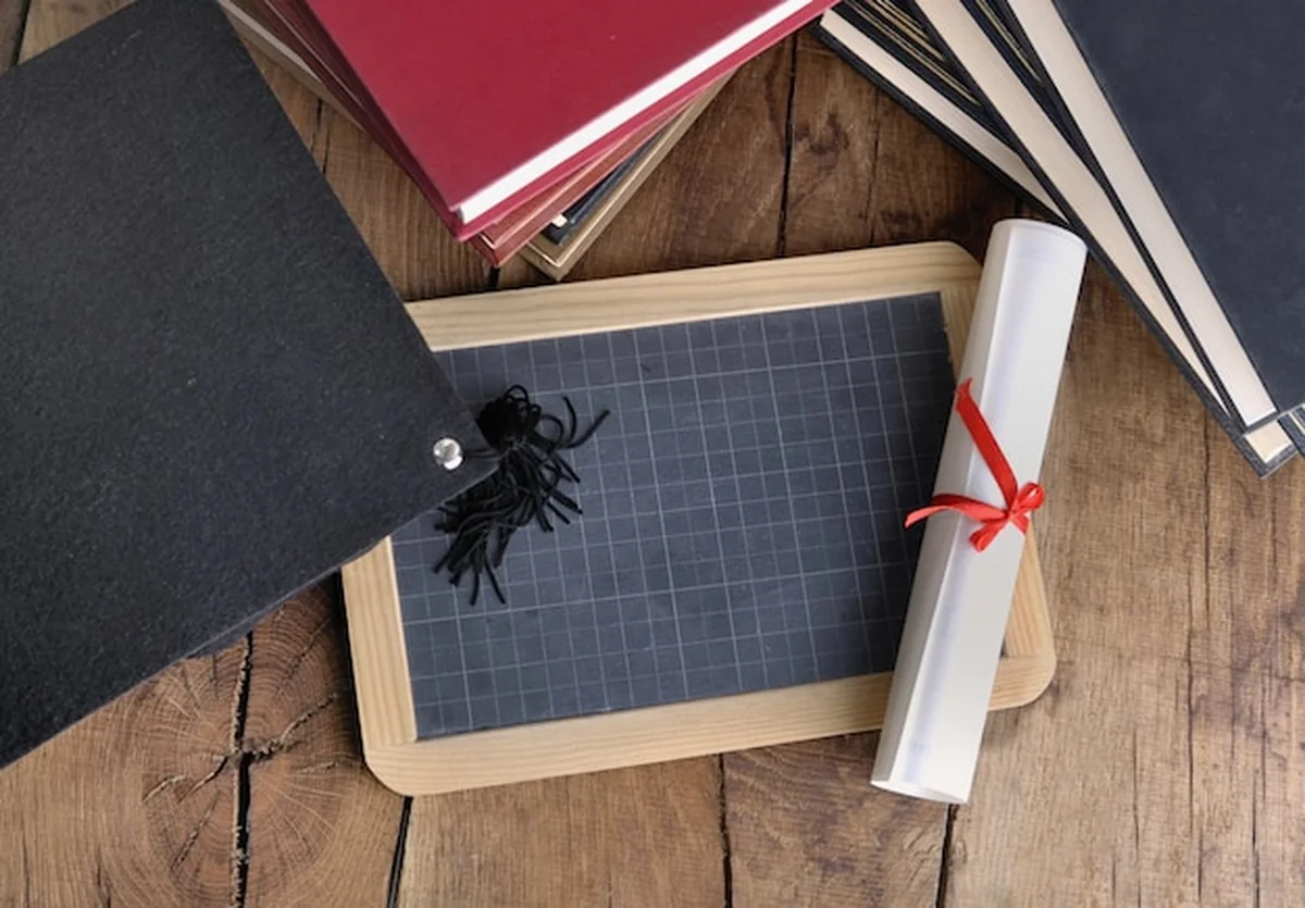 Dyplom na drewnianym stole z tablicy szkolnej i graduacyjnej