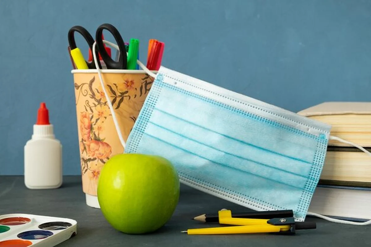 Książki, jabłka i maska medyczna na artykułach do nauki w szkole
