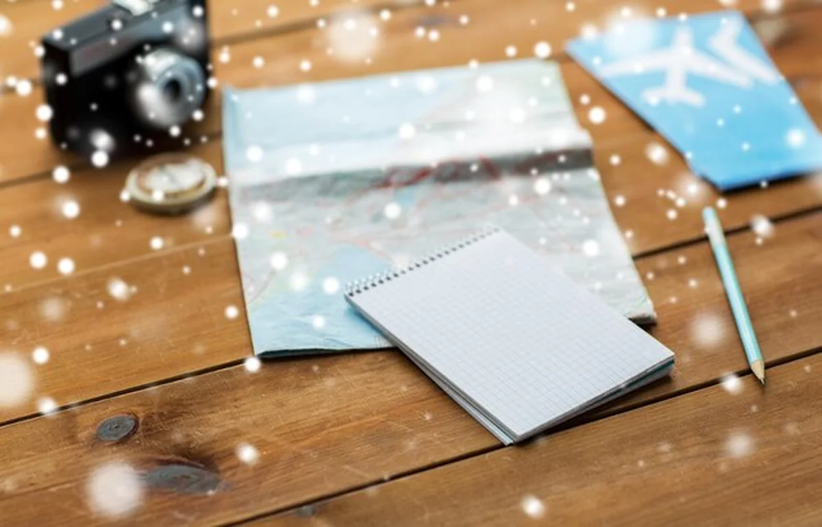 Notatnik z mapą, aparatem i biletami lotniczymi na śnieg