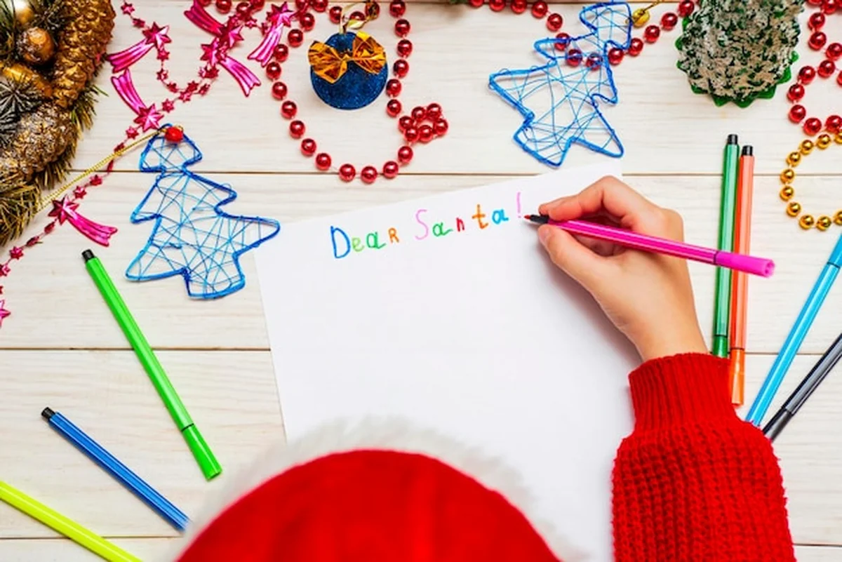 Małe dziecko pisze list do Świętego Mikołaja przy stole