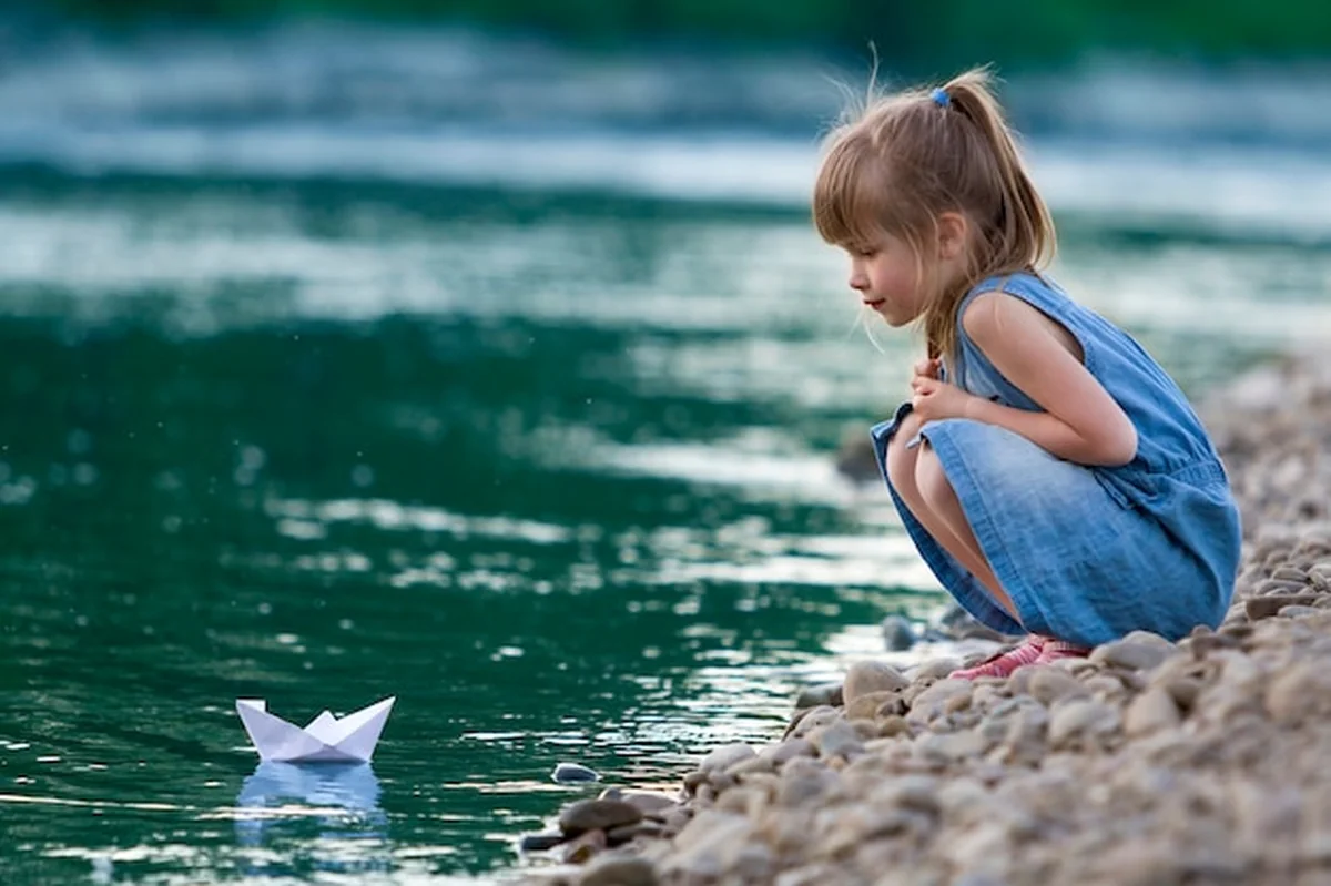 Dziewczynka bawiąca się origami na riverbanku