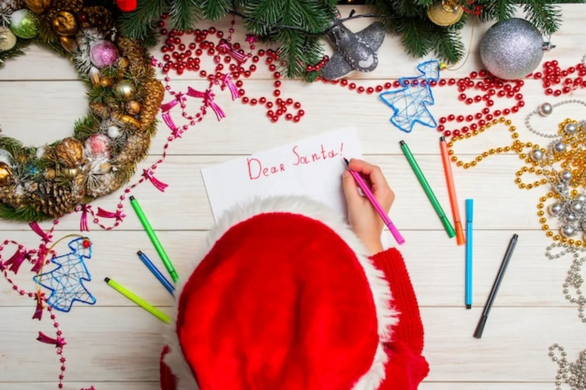 Małe dziecko pisze list do Świętego Mikołaja przy stole
