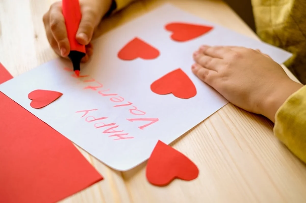 Dzieci piszą kartkę z życzeniami na walentynki z sercami