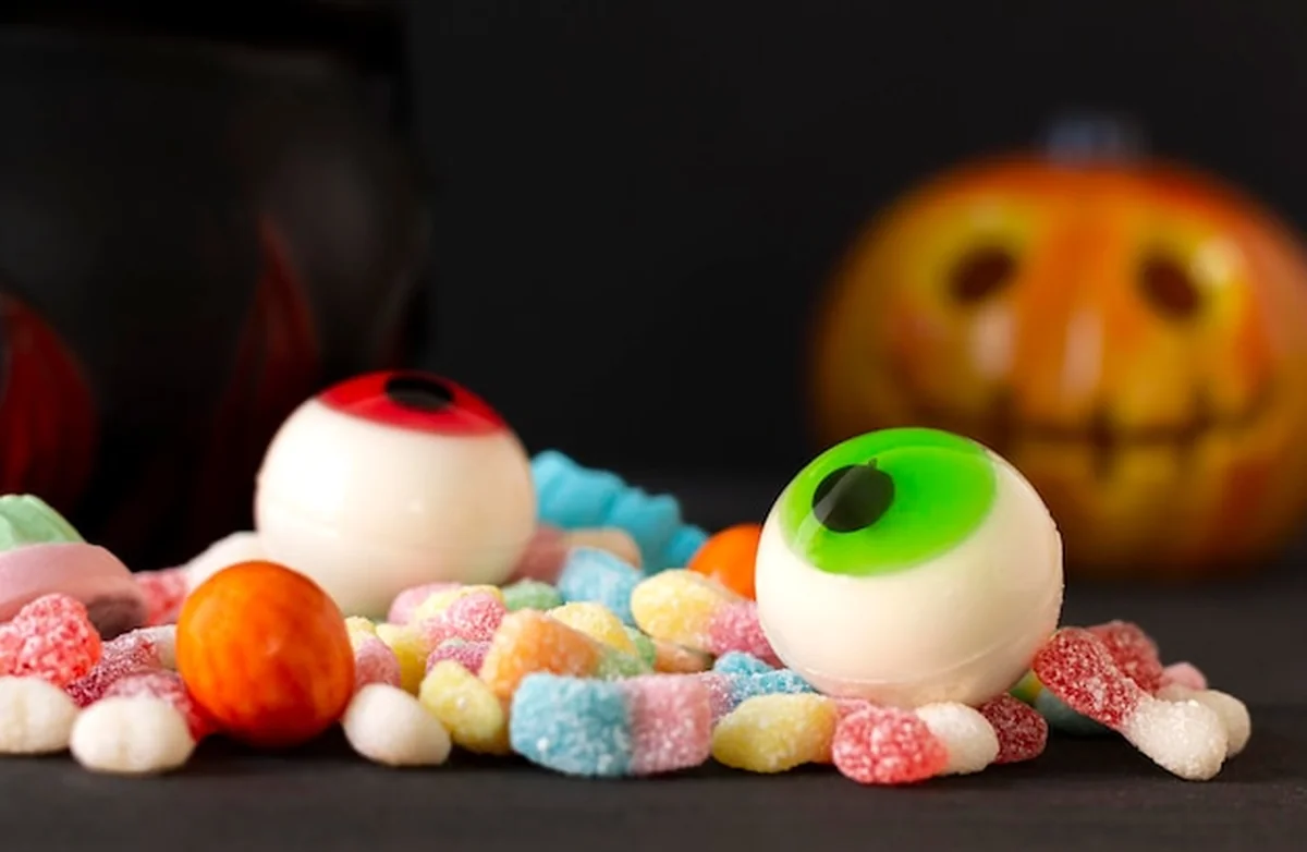 Pomarańczowa dynia z kolorowymi cukierkami na Halloween